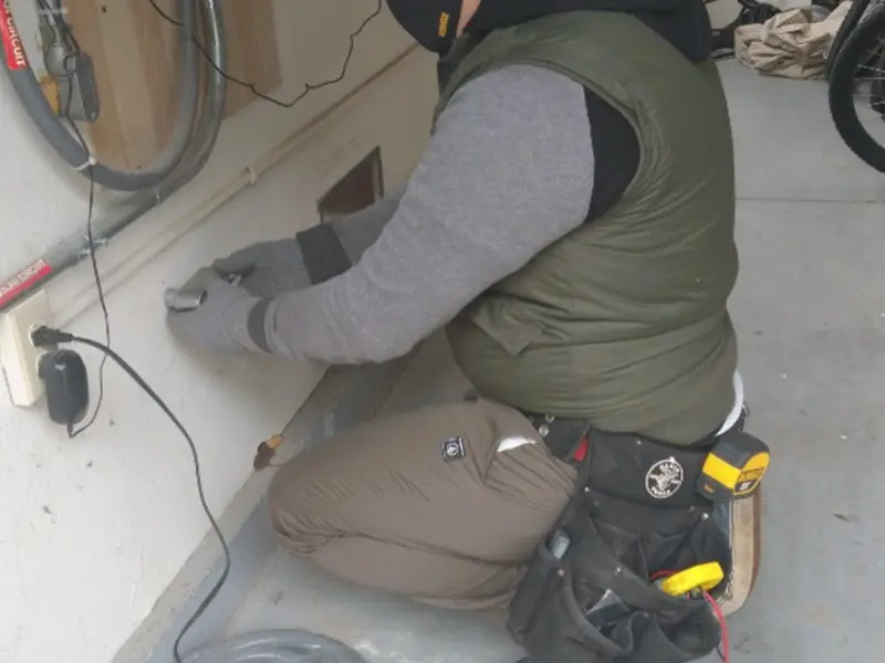 Electrician performing outlet wiring in a Harrison garage